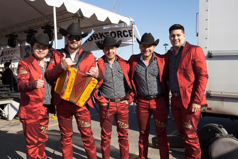 5 guys uniformly dressed in sharp red suits and black cowboy hats.