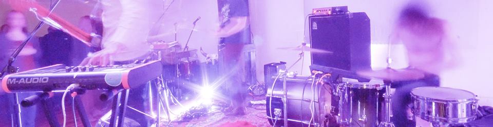 Distorted purple photograph of a blurry band playing on a stage