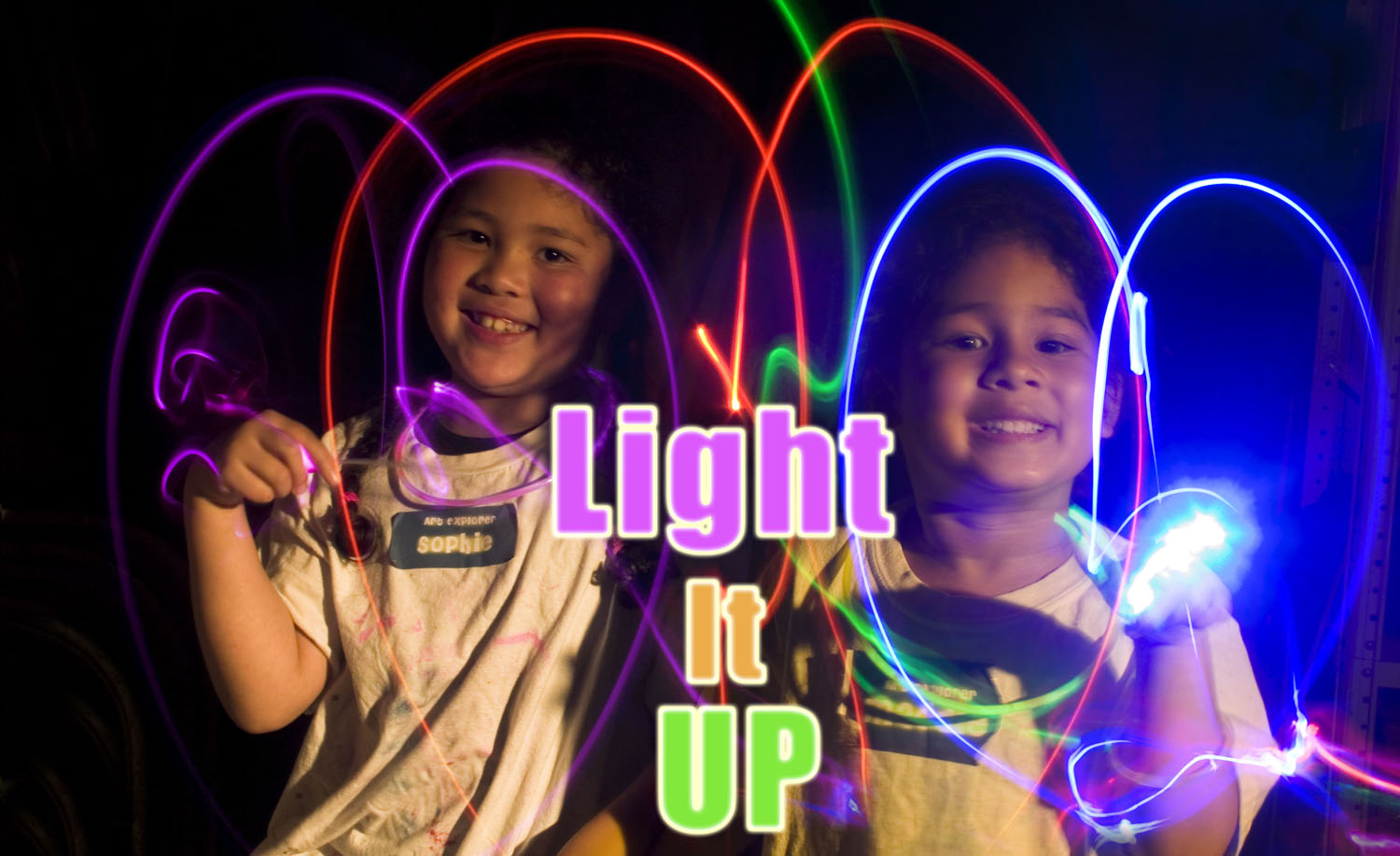 two smiling children wave glowsticks