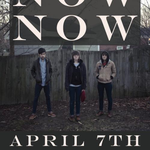 Three people wearing jackets standing in front of a wooden fence