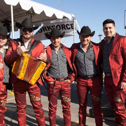 5 guys uniformly dressed in sharp red suits and black cowboy hats.