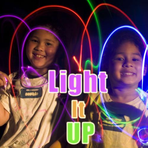 two smiling children wave glowsticks